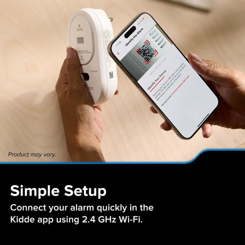 Person setting up Smart Carbon Monoxide Detector With Plug In Design And AA Battery Backup, using app on smartphone