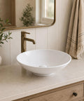 Sinkology Sagan 16.5 Inch Round Vessel Bathroom Sink, Crisp White Vitreous China Above-Counter Vanity Bowl with Drain and Coordinating Cap, No Overflow on a countertop.