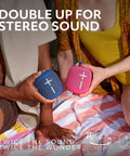 Two people holding blue and pink Wonderboom 4 Portable Bluetooth Speakers with Waterproof Floating Design outdoors.