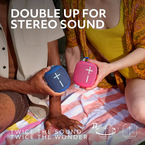 Two people holding blue and pink Wonderboom 4 Portable Bluetooth Speakers with Waterproof Floating Design outdoors.