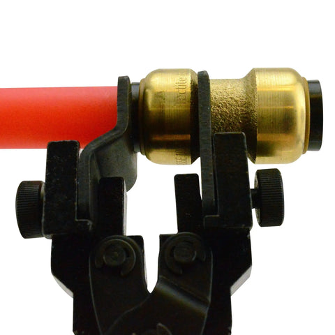 No Fuss Push To Connect Plumbing Tool gripping brass fitting on red pipe, with ratcheting grip, interchangeable faceplate visible.