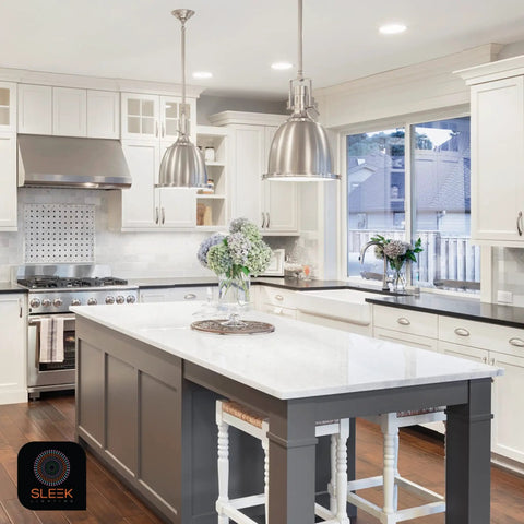 Modern kitchen with white cabinets and large island, featuring overhead pendant lights illuminating the space.