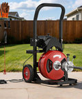 Heavy Duty Electric Drain Cleaner With Automatic Feed And Air Activated Foot Pedal To Kick Stubborn Pipe Clogs To The Curbs In Two To Four Inch Bathroom And Kitchen Lines on display with gloves and accessories.