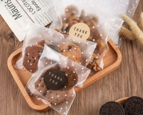 4x4 Cookie Bags With Thank You Stickers, Self Sealing Clear Cellophane Bags filled with cookies, displayed on a wooden tray