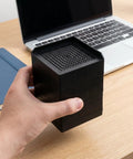 Hand holding 2 Pack Silicone Furniture Pads For Table And Chair Legs Square 3.35 Inch Nonslip Noise Reducing Foot Pads on desk