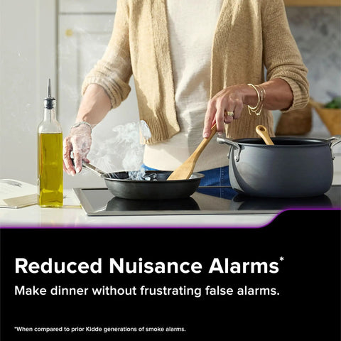 Person cooking in a kitchen with app enabled hardwired smart smoke and carbon monoxide detector with AA battery backup nearby