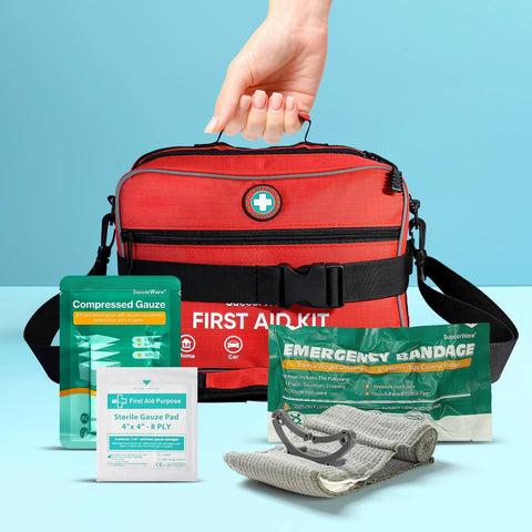 Red first aid kit bag with black straps; visible contents include compressed gauze, gauze pads, emergency bandage.