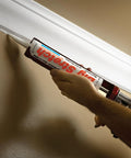 High Performance Elastic Sealant Cartridge 10.5 Oz In Natural Sandstone being applied to trim in home repair.