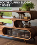Contemporary wooden shelving unit with glass doors, displaying plants and kitchenware in a living room setting.