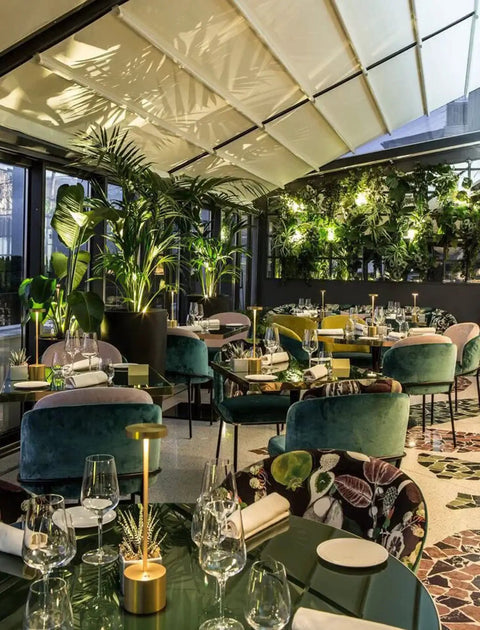 Outdoor restaurant setting with 2 Pack Cordless Rechargeable LED Table Lamps With 5000mAh Battery on tables, surrounded by greenery.