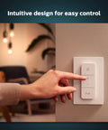 Hand operating 2 Pack Indoor Hue Wall Switch Modules For Smart Lighting Keeps Your Hue Lights Reachable When Off, Easy Install Behind The Switch, Requires Hue Bridge For Full Remote Control, Automations, And Smarter Scenes on a modern wall