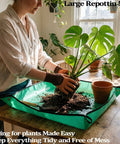 Person using large green repotting mat on wooden table with Monstera plant, showcasing clean potting process.