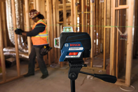 Boss Class 12V Max Three Plane Green Beam Laser Level on stand in construction site, with contractor using laser for alignment.