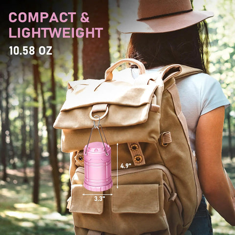 Pink LED Camping Lanterns With Portable Handle hanging on a tan backpack in forest, compact design for hiking