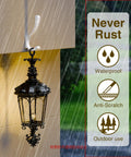 Black outdoor lantern hanging on a wall during rain with icons stating 'Never Rust,' 'Waterproof,' 'Anti-Scratch,' and 'Outdoor Use'