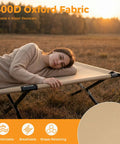 Person lying on Extra Wide Camping Cot For Adults With 30.3 Inch Sleep Space No Squeeze Comfort Foldable Army Bed in field