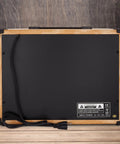 Back view of 40W Electric Guitar Amp With 8-Inch 4-Ohm Speaker, showing power cord and input label on wooden surface.