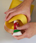 Person inserting item into Eco Lite Golden Kraft Self Sealing Bubble Mailer 6.5 By 10 Inches With Finned Edges And Duraliner Cushioning