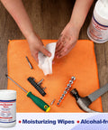 Hands using Lead Remover Wipes For Shooting 2 Pack 120 Wipes Hand And Surface Cleaning Wipes near tools on orange mat.