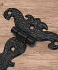 Antique T Strap Hinge in black zinc alloy on wood surface, part of a four-piece set for cabinets and decorative projects, 4.45x2.76 inches.