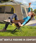 Person relaxing in Zeta L8 Max Camping Chair with Carry Bag, 25 degree gentle tilt, beside a large beige tent, outdoor setting.