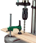 No Nonsense Quick Adjust Drill Press Hold Down with heavy rubber foot gripping a wooden workpiece during drilling.