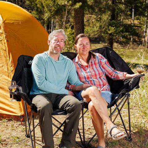 Couple seated on Two Person Oversized Camping Chair Loveseat For Adults Heavy Duty Folding Outdoor Couch Black Portable Patio Lawn Chair