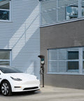 Ride-Ready Outdoor EV Charging Pedestal Housing a Tough Steel Hood Shielding Plug-In Wheels From Storms near a white car.