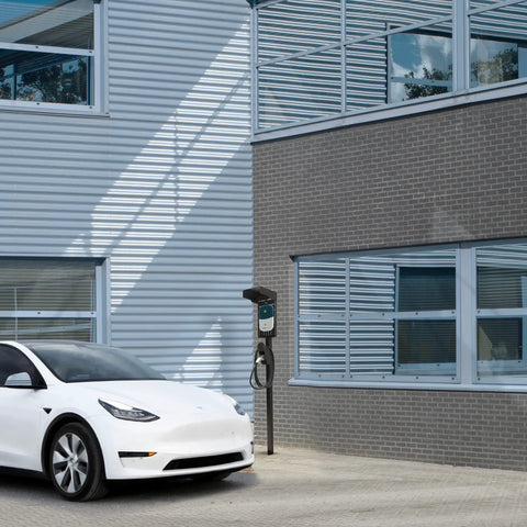 Ride-Ready Outdoor EV Charging Pedestal Housing a Tough Steel Hood Shielding Plug-In Wheels From Storms near a white car.