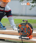 Worker using a saw near a 60 Ft Cord Reel With Four Outlets 14 AWG SJTW Cable Workhorse Heavy Duty Extension Cord Reel on a table.