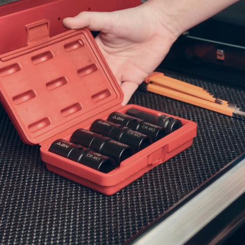 Hand holding a red case with Double Sided Lug Nut Socket Set Five Piece Half Inch Drive Flip Impact Sockets on black surface