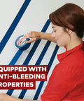 Person applying blue painter tape to wall for sharp paint lines. Blue Painter Tape Bulk 1.88 Inch by 60 Yards 24 Pack 1440 Yards Total Sharp Edge