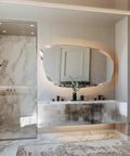 Modern bathroom with marble walls and a glass shower enclosure featuring a matte black shower hose and sleek fixtures.