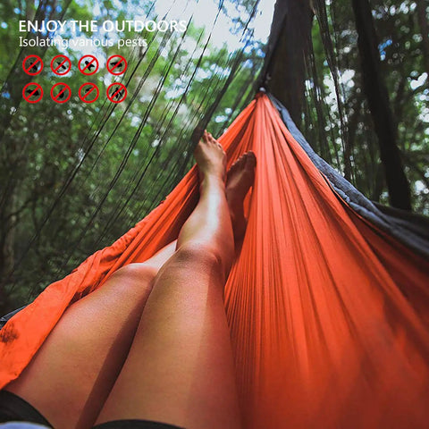 Person relaxing in an orange hammock with Camping Hammock Net With 360 Degree Mosquito Protection in a forest setting.