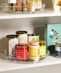 Smooth As Butter 4 Pack Lazy Susan Turntables on shelf, clear plastic rotating trays with jars, spices, and condiments.