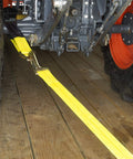 Two Inch Wide By Thirty Six Inch Long Premium Axle Tie Down Strap With D Rings securing tractor on wooden trailer bed