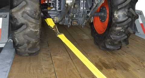 Two Inch Wide By Thirty Six Inch Long Premium Axle Tie Down Strap With D Rings securing tractor on wooden trailer bed