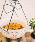 Heavy Duty No Burn Bowl Gripper Slick Stainless Steel Heat Resistant Pot Tongs lifting white bowl of almonds, non slip handle visible.