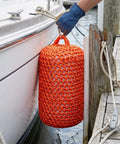 Solid Nylon Boat Fenders For Docking And Marine Anti Collision Protection in orange, cushioning a boat hull dockside.