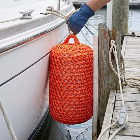 Solid Nylon Boat Fenders For Docking And Marine Anti Collision Protection in orange, cushioning a boat hull dockside.