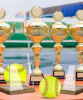 Clear Acrylic Softball Display Case with Wood Base for one ball next to gold trophies, showcasing a softball, dustproof cube