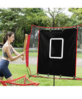 A woman practicing with a Backstop 4Ft By 6Ft Batting Cage Target Backdrop With Strike Zone, featuring weatherproof PVC, in a park.