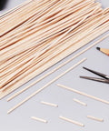 60 Pieces Unfinished Square Dowels One Eighth Inch Square Cross Section And Twelve Inches Long For DIY Molding Craft Projects Woodworking Perfect For DIYers And Makers, scattered on a table with tools.