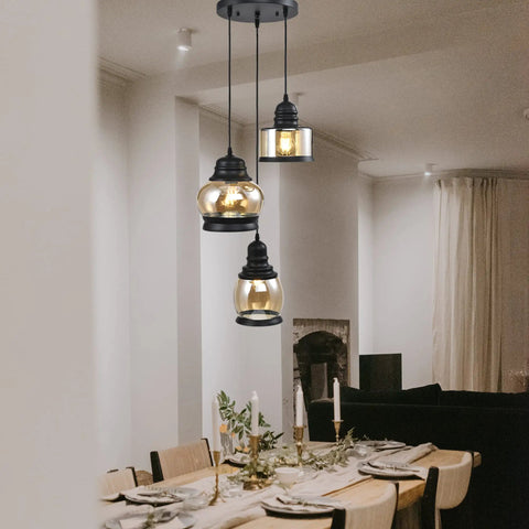 Three Light Modern Glass Pendant Chandelier for Dining Room and Kitchen Island with Amber Glass Shades hanging over a dining table.