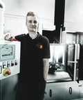 Person in a black uniform leaning on control panel of electrical equipment, representing use context for Six Piece Insulated Screwdriver Set With Lasertip Slotted And Phillips Tips For Electricians 10000 Volt Tested To 1000 Volt Working Standards Pro Grade Handles For Heavy Duty Electrical And Home Projects.