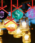 Colorful Christmas ornaments hanging with lights, featuring merry designs and letters. Pre Ed Sublimation Transfer Sheets shown in use.