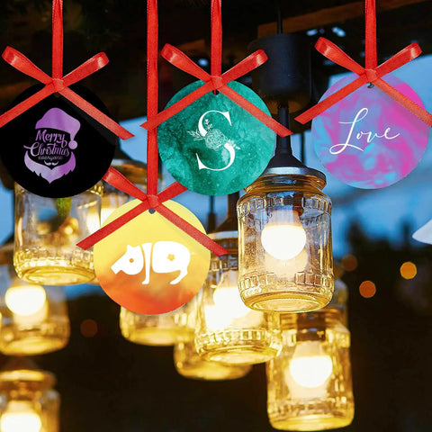 Colorful Christmas ornaments hanging with lights, featuring merry designs and letters. Pre Ed Sublimation Transfer Sheets shown in use.