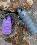 Two Pack Collapsible Silicone Water Bottles 500ml Each, purple and grey bottles in stream, ideal for travel and outdoor use.