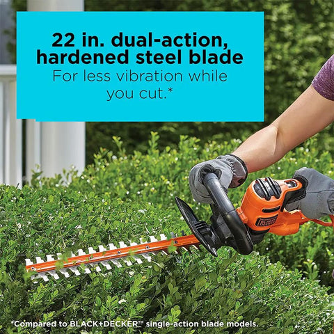 Person using a 22 Inch Electric Hedge Trimmer with Dual Action Blades and Full Wraparound Handle on green shrubs