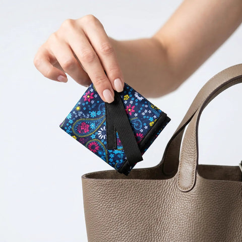 Hand placing Silver Enhanced Pee Cloth For Women Hiking On The Go Travel Urinal Alternative into a tote bag